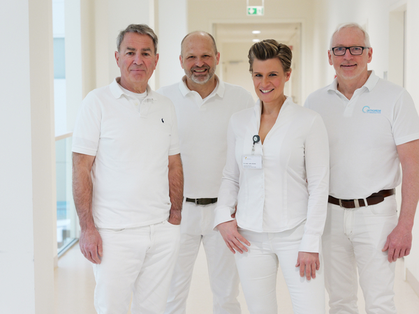 Dr. med. Dirk Rose, Lars Witthöft, Zentrumsleiterin Dr. med. Julia M. Reinke, MHBA, und Dr. med. Bernd Augustin vom Albertinen EndoProthetikZentrum im Albertinen Krankenhaus in Hamburg-Schnelsen stehen in weißer Funktionskleidung in einem Stationsflur und blicken lächelnd in die Kamera. Dr. med. Dirk Rose, Lars Witthöft, Zentrumsleiterin Dr. med. Julia M. Reinke, MHBA, und Dr. med. Bernd Augustin vom Albertinen EndoProthetikZentrum im Albertinen Krankenhaus in Hamburg-Schnelsen stehen in weißer Funktionskleidung in einem Stationsflur und blicken lächelnd in die Kamera.